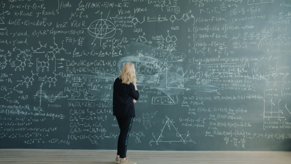 Woman in front of chalkboard with complex equations